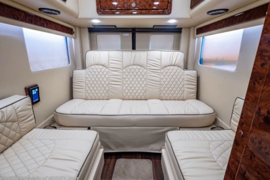 Spacious RV rental interior with luxury cream quilted seating and wood trim. Transforms for comfort.