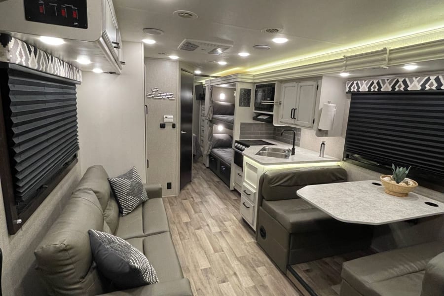 Spacious RV rental interior featuring a modern kitchen, dinette, and sofa, perfect for comfortable travel.