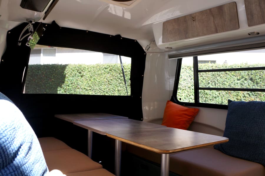 Modern rv rental interior: bright dining area with comfy benches, large windows, & scenic views. Ideal for travel.