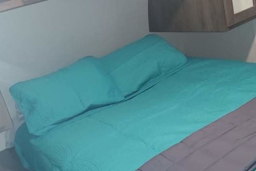 RV rental bedroom: a comfortable space with teal bed, overhead cabinets, and built-in mirrored storage.