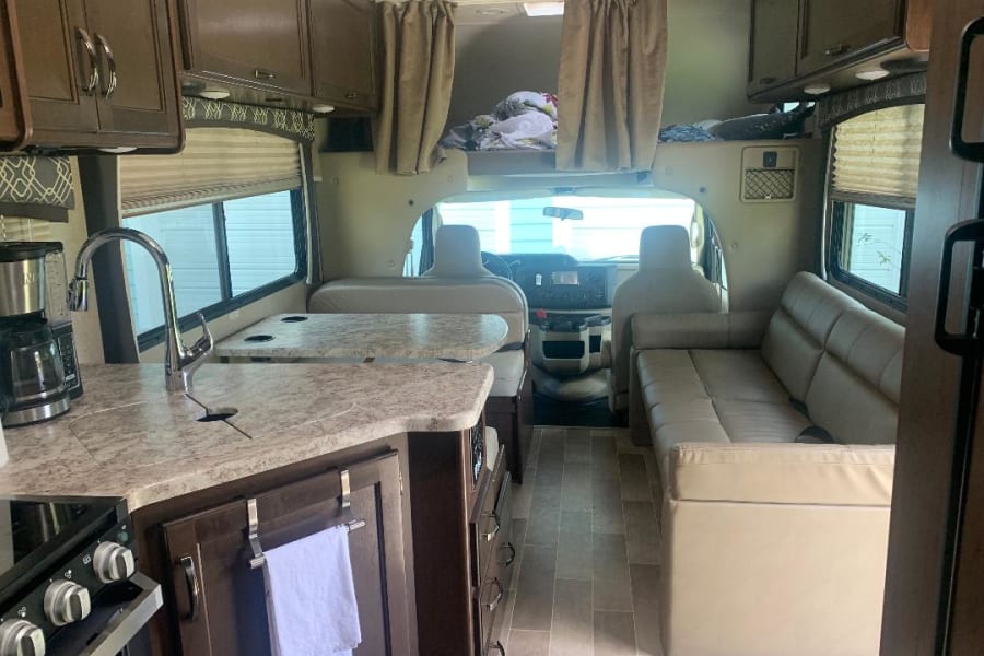 Spacious rv rental interior featuring a full kitchen with sink, dinette, and comfortable sofa, ready for adventure.