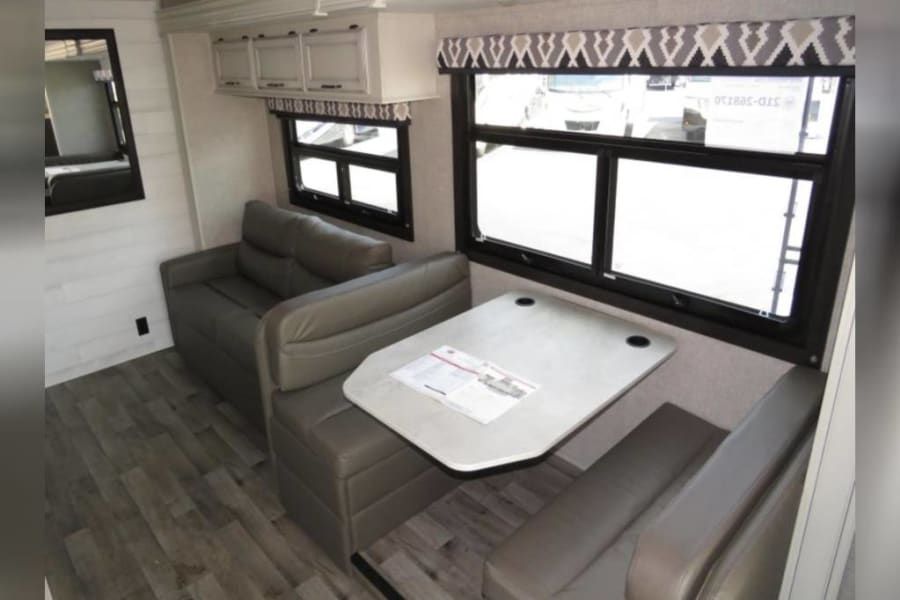 RV rental: inviting interior with dinette, sofa, overhead cabinets, and large windows.