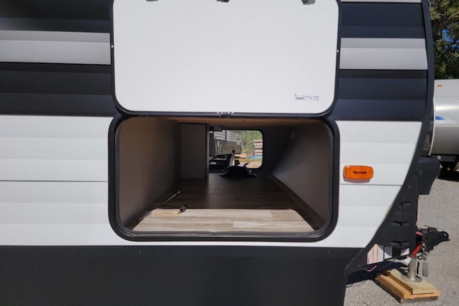 This RV rental travel trailer features a spacious, open pass-through storage compartment with a wooden floor.