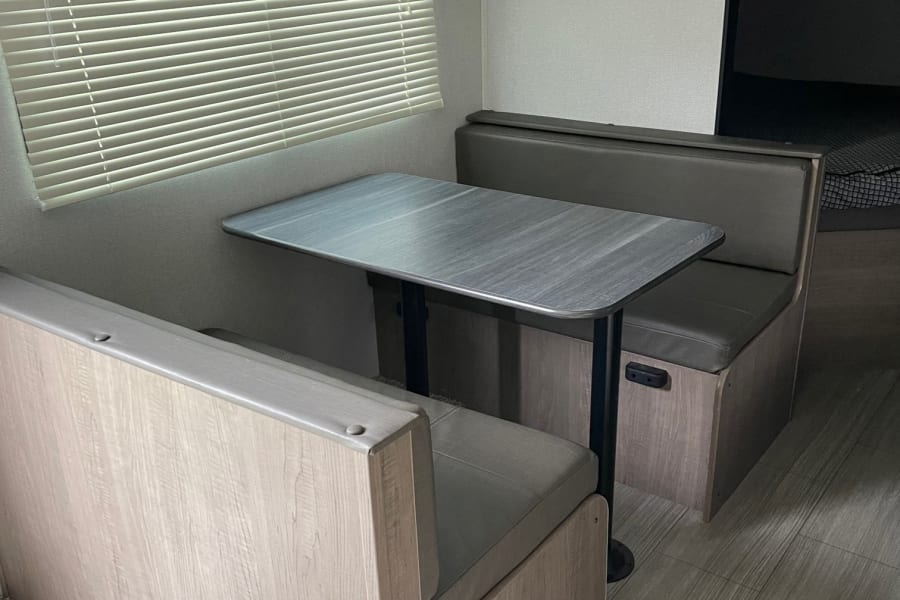Cozy RV rental dinette with comfortable benches and a table, ideal for meals and relaxation inside your RV.