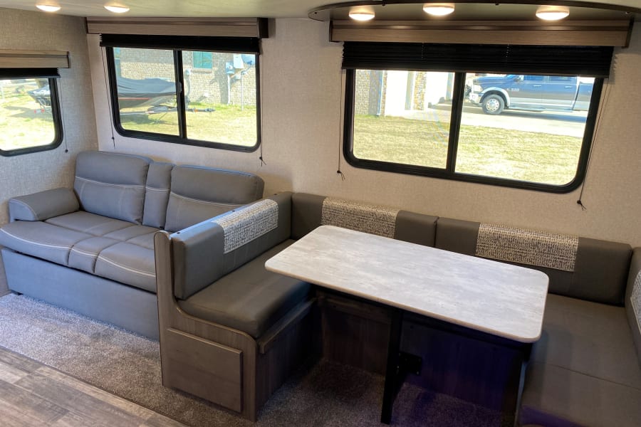 Inside this modern rv rental: a comfy gray sofa that converts to a bed, plus a cozy dinette for dining and seating.
