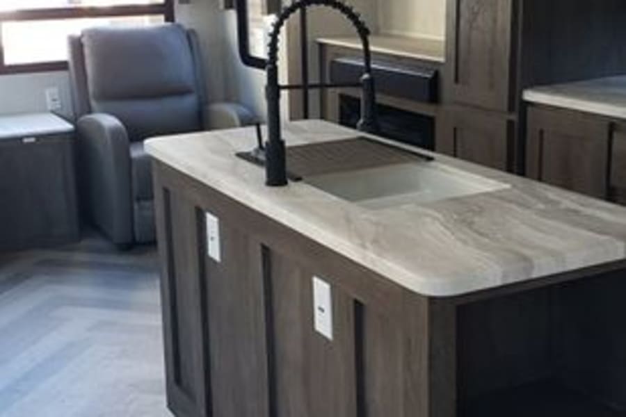 Experience comfort in this modern rv rental. Spacious interior with kitchen island, lounge area, and stylish herringbone flooring.