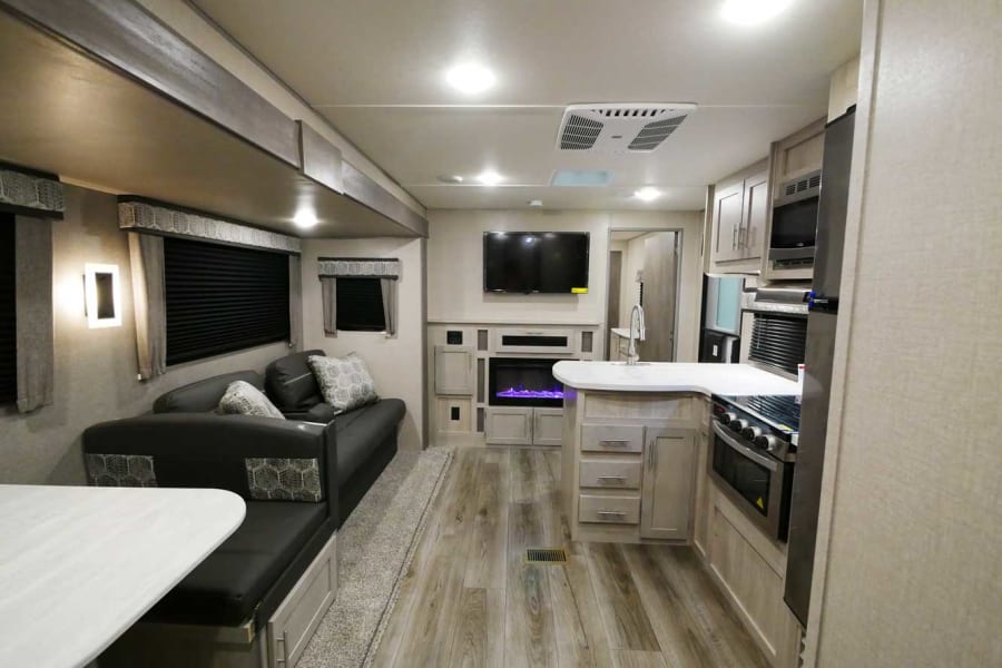 Spacious RV rental interior with a modern kitchen, living area, fireplace, and comfortable furnishings for travel.