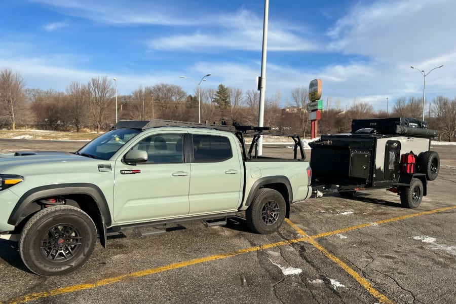 Light green Toyota Tacoma towing a compact black & grey off-road trailer, ideal for an rv rental adventure or camping.