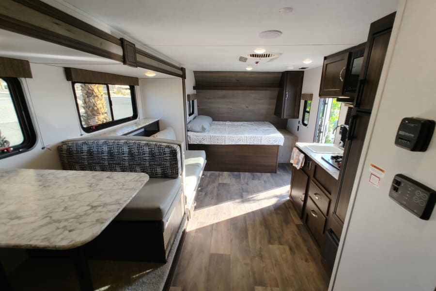 Bright RV rental interior showcasing a cozy dinette, comfortable bed, and functional kitchen. Ideal for adventure.