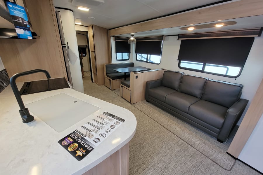 Spacious RV living area for your next rv rental, featuring a modern kitchen, comfortable dinette, and sofa.