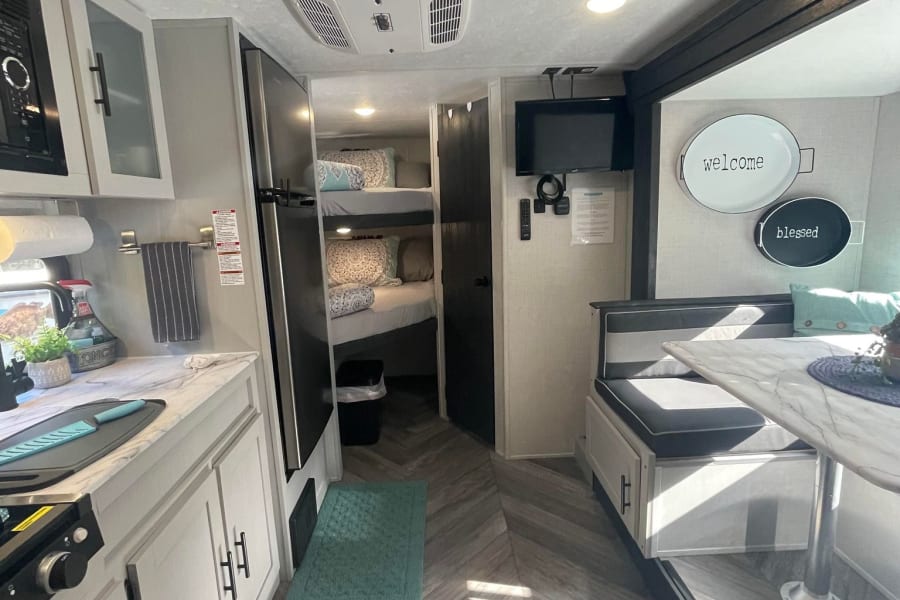Modern RV rental interior with kitchen, dinette, and bunk beds, offering a bright and comfortable living space.