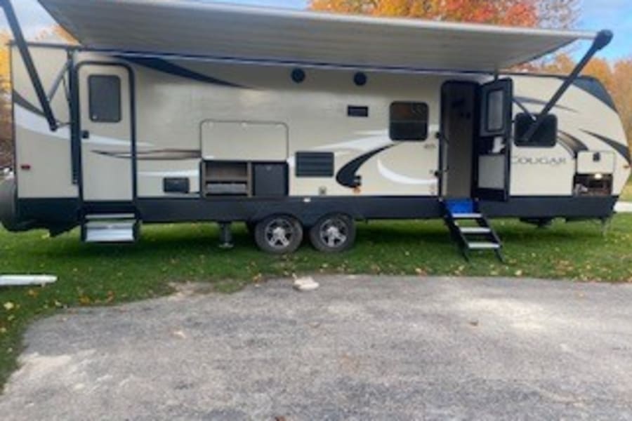 An inviting travel trailer RV rental, with awning extended and steps down, ready for your camping adventures.