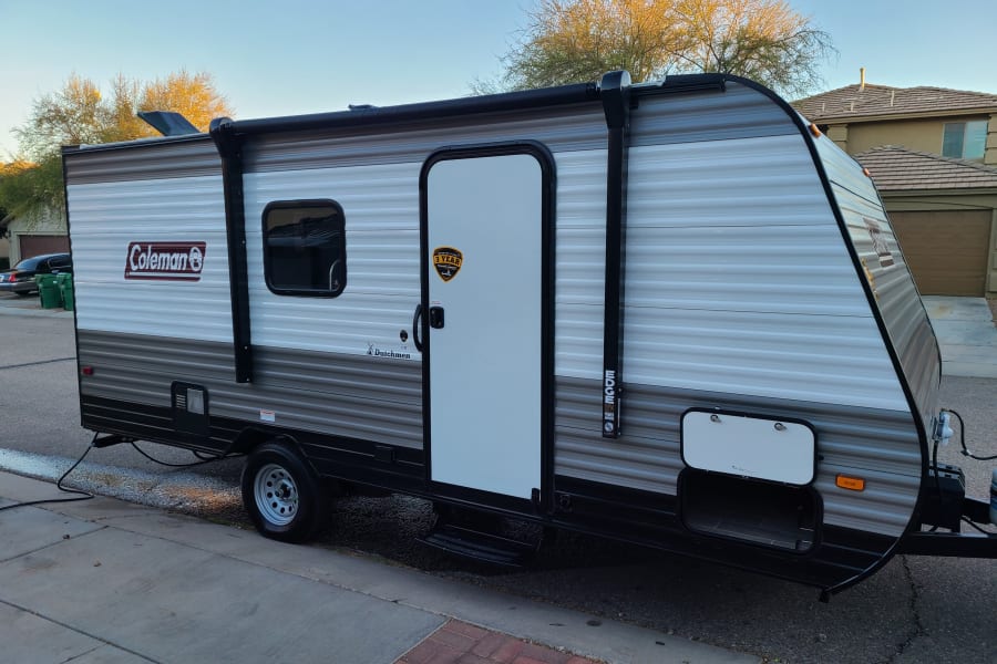 Coleman Dutchmen travel trailer, a modern RV rental with 12V power awning, parked roadside.