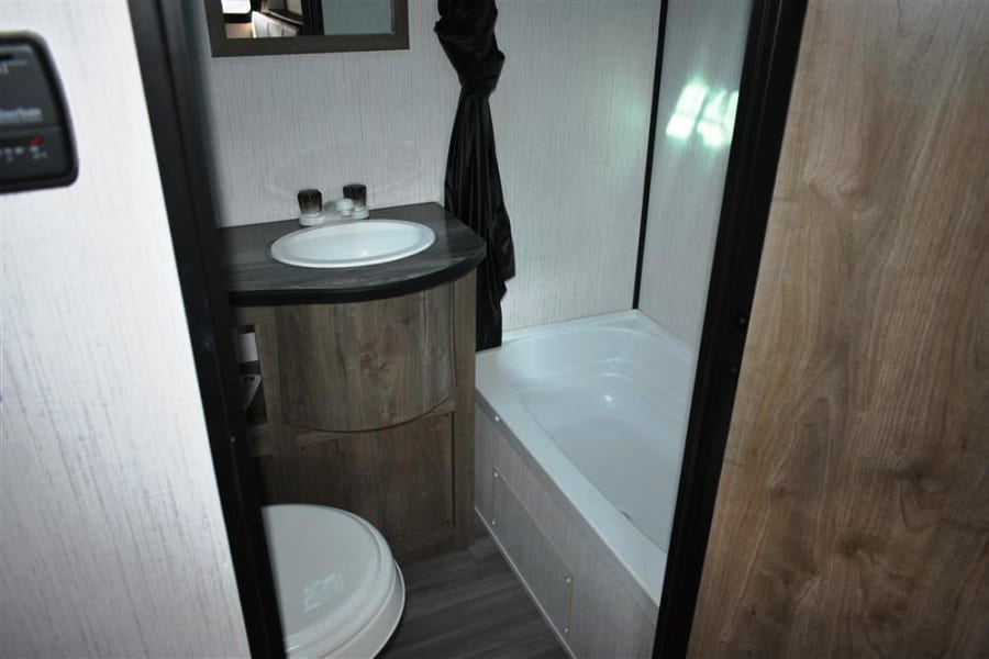 Inside an RV rental bathroom: complete with a compact vanity sink, toilet, and bathtub/shower combo.