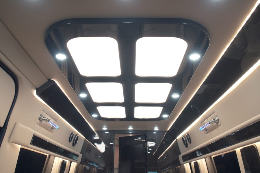 Luxurious RV rental interior with modern ceiling lights, ambient strip lighting, and upscale finishes for comfortable travel.