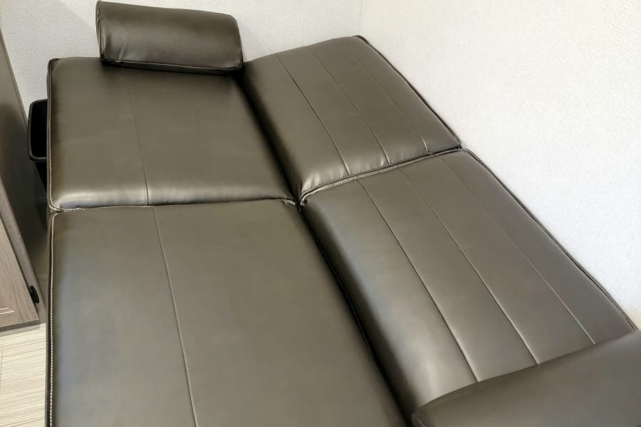 Dark gray faux leather RV sofa with stitched cushions, a comfy seating option for your RV rental.