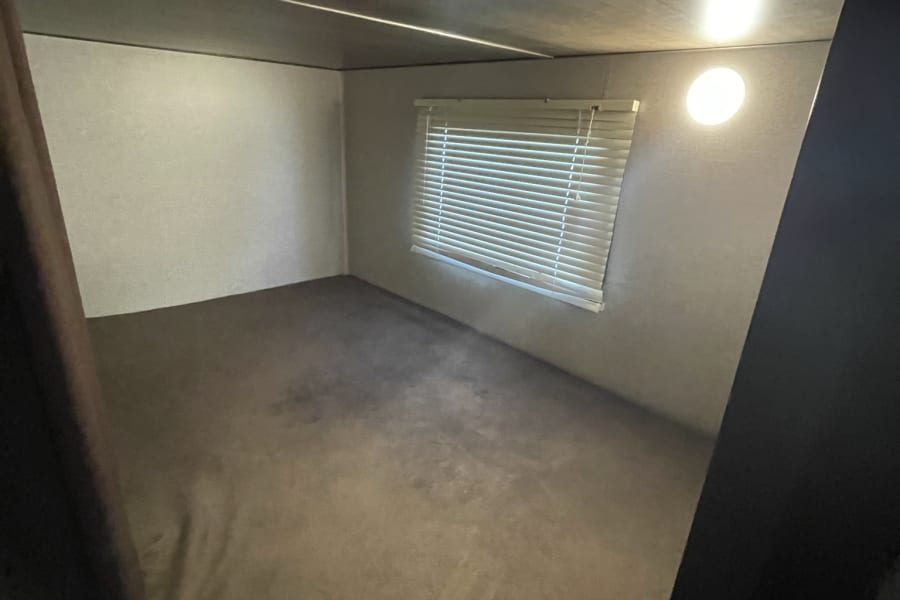 RV rental: Compact bunk bed area with a window, blinds, and overhead light.