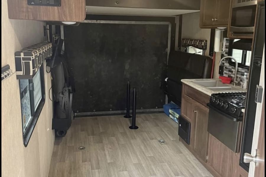 Bright RV rental interior with full kitchen, wood flooring, and versatile cargo area. Your spacious home on wheels awaits your adventure!