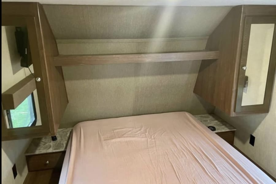 Cozy RV bedroom with bed, overhead storage, and nightstands. Perfect for your next rv rental adventure.