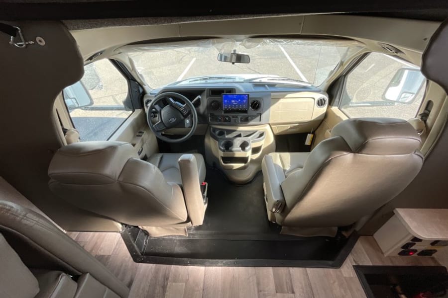 RV rental interior: Front cabin with tan seats, dashboard, and steering wheel, ready for your next road trip.