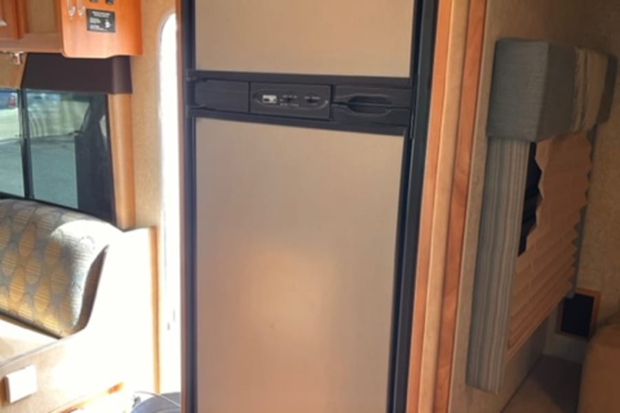 RV rental interior shows a large two-door fridge, convertible bed, and ample storage for your journey.
