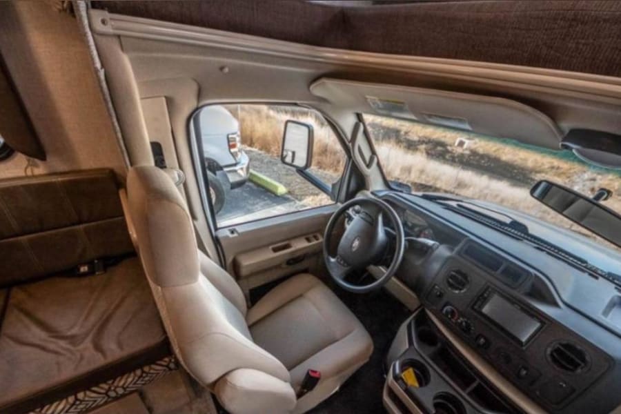 Spacious RV rental interior showcasing the driver's cockpit, steering wheel, and front dashboard.