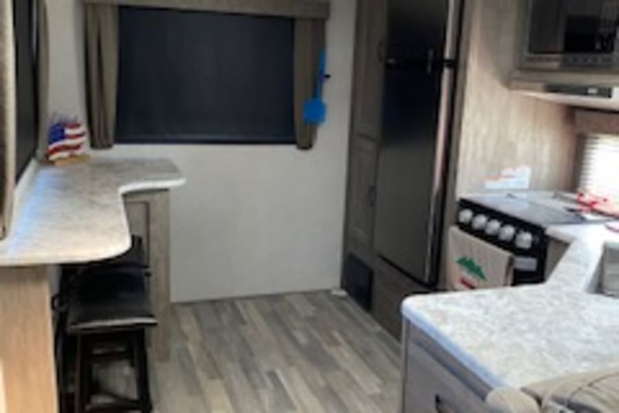 RV rental interior showing a compact kitchen, living space with sofa, and wood-look flooring.