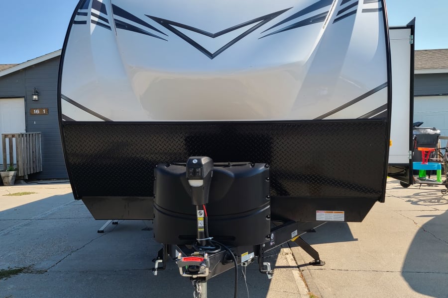 A white Tracer travel trailer (RV) shown from the front, parked on pavement, ready for rv rental.