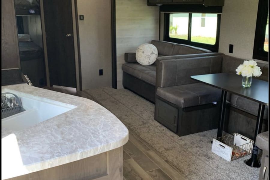 Spacious RV rental interior featuring a bright kitchen, U-shaped dinette, comfy lounge, and bunk beds. Ideal for travel.