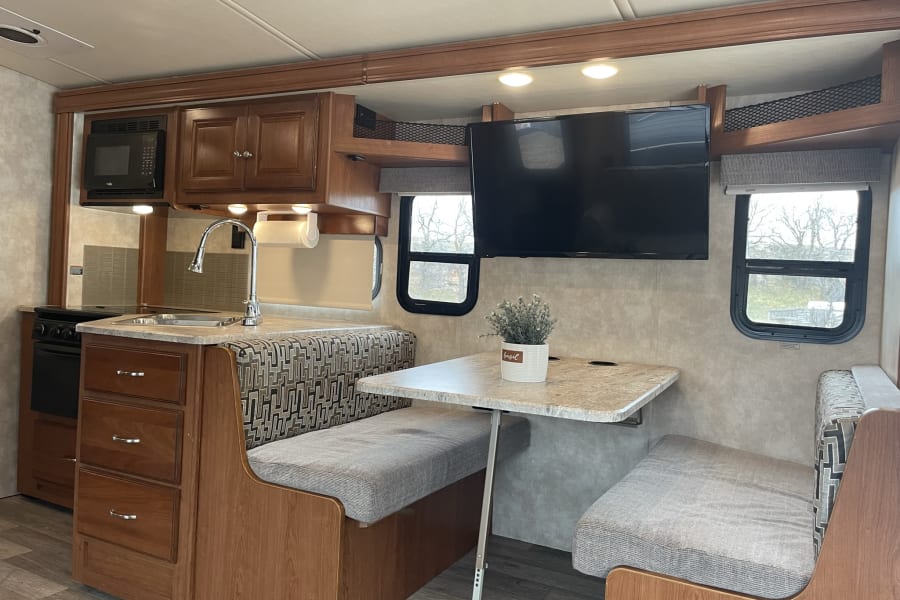 Spacious RV rental interior with full kitchen, dinette, TV, and comfortable seating. Perfect for your next road trip adventure.