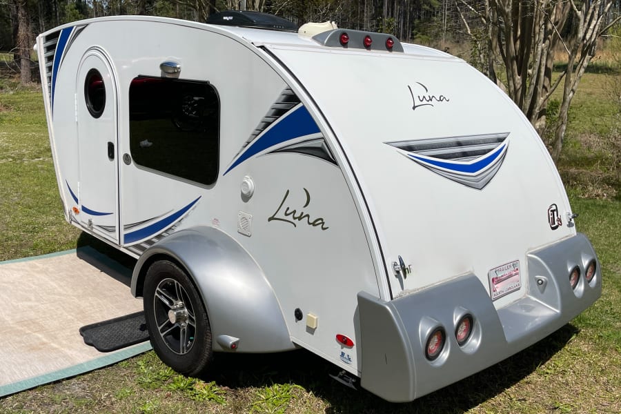 This white Luna teardrop RV camper with blue accents is ready for your next rv rental outdoor adventure.