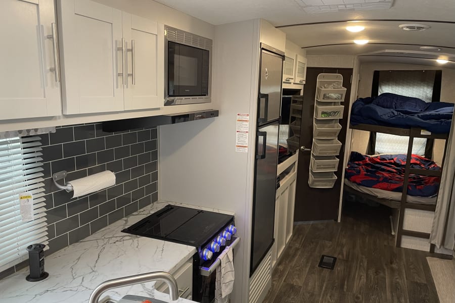 Spacious RV rental interior with modern kitchen and bunk beds, perfect for family travel.