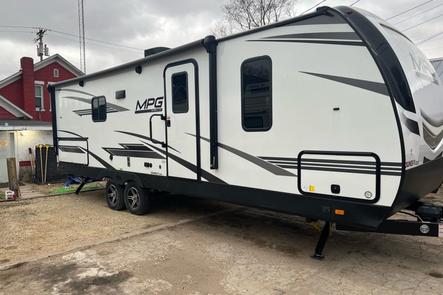 Modern white MPG Ultra-Lite travel trailer, ideal for your next RV rental adventure. Parked on a gravel lot.