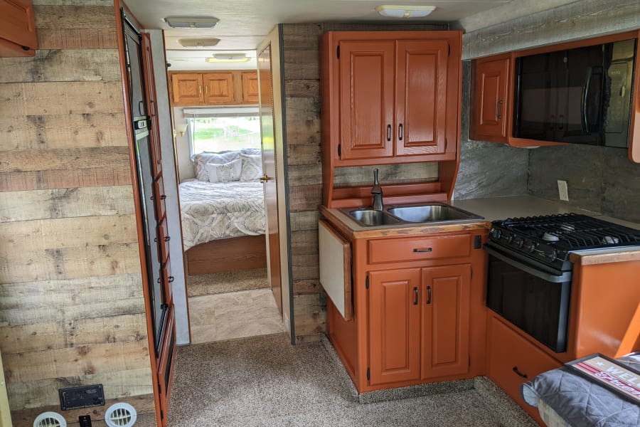 Stove, oven, fridge and freezer, microwave, and sink. Cabinets are stocked with essentials. 