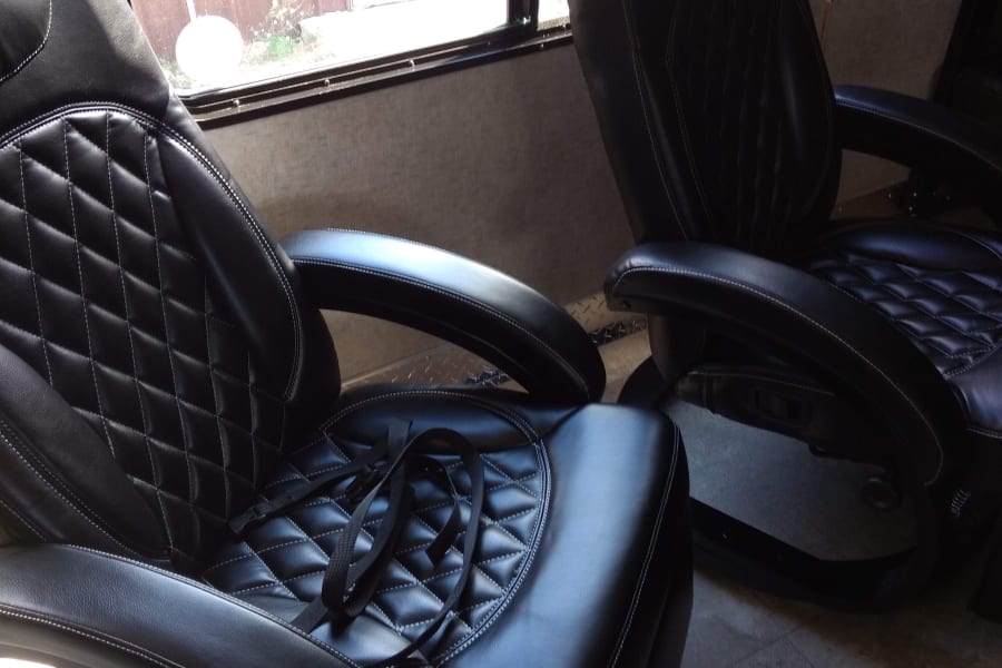 Two black leather recliners with diamond quilting, one with straps, offer comfort in this RV rental.