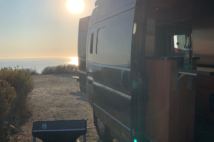 Enjoying a stunning sunset ocean view from our cozy RV rental. Perfect van life evening with wine.