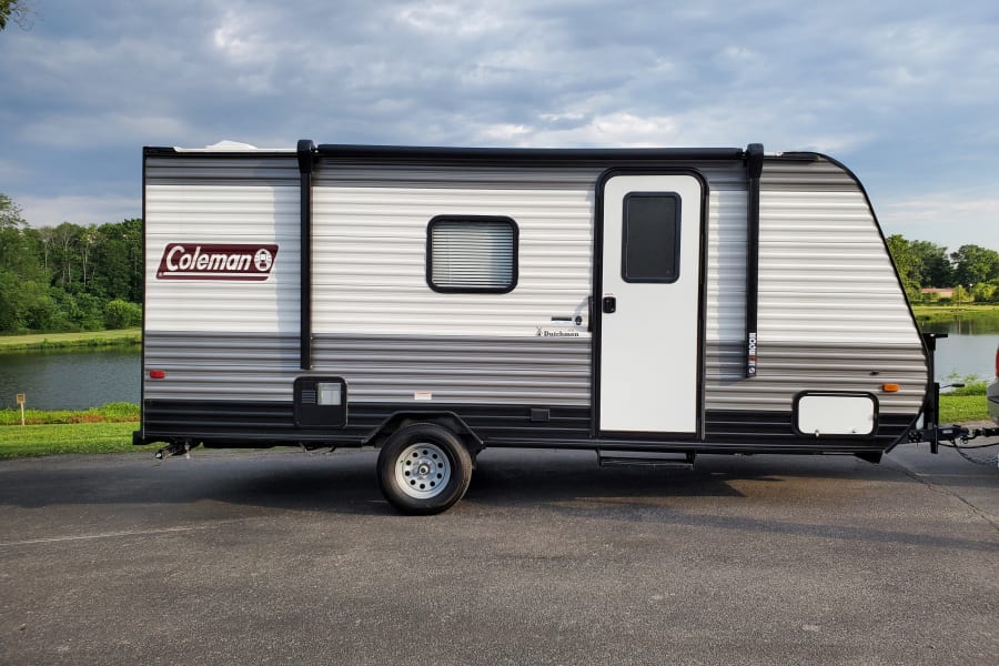 Coleman travel trailer, a great RV rental for lakeside adventures under cloudy skies.
