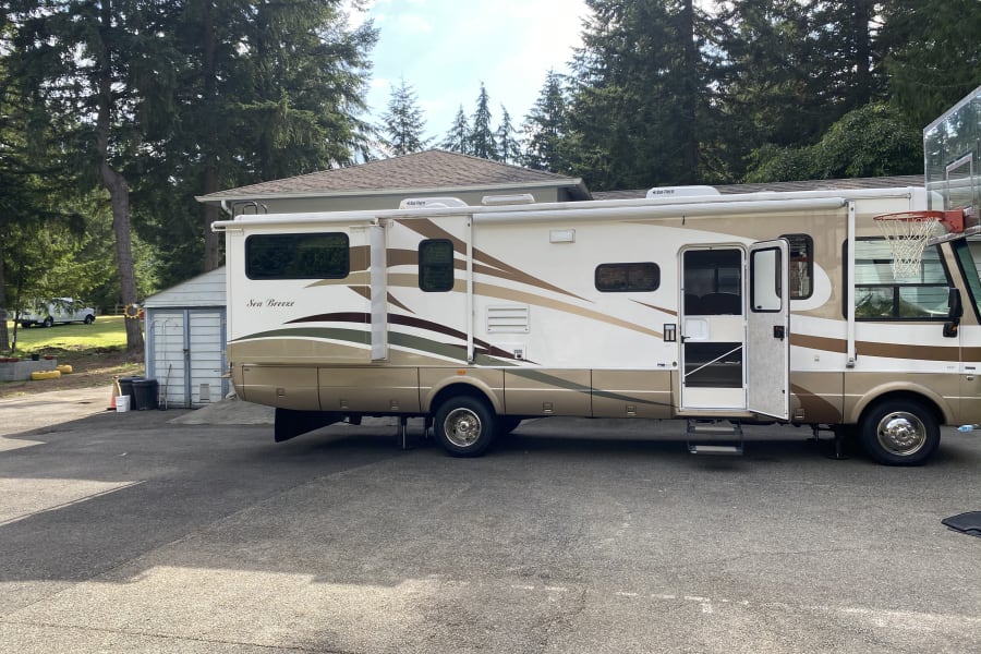 Spacious Sea Breeze RV rental parked on a driveway with its side expanded and door open, ready for use.