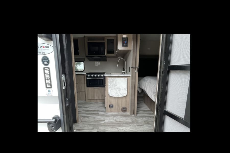 Step into this modern travel trailer rv rental, showcasing a full kitchen and cozy bed for your adventures.