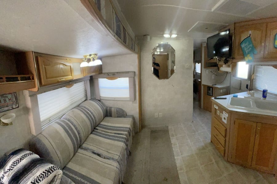 RV rental interior: cozy living area with striped sofa, plus a kitchen equipped with a sink and TV.