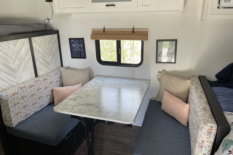 Explore this stylish RV rental dinette featuring comfortable seating, a marble table, and bright decor for your next adventure.