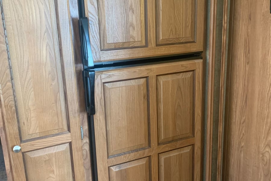 RV rental: view of wooden cabinetry and an integrated Dometic refrigerator with paneling.