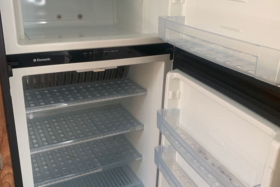 Clean, empty Dometic RV refrigerator and freezer with shelves and door bins, ready for your next rv rental.