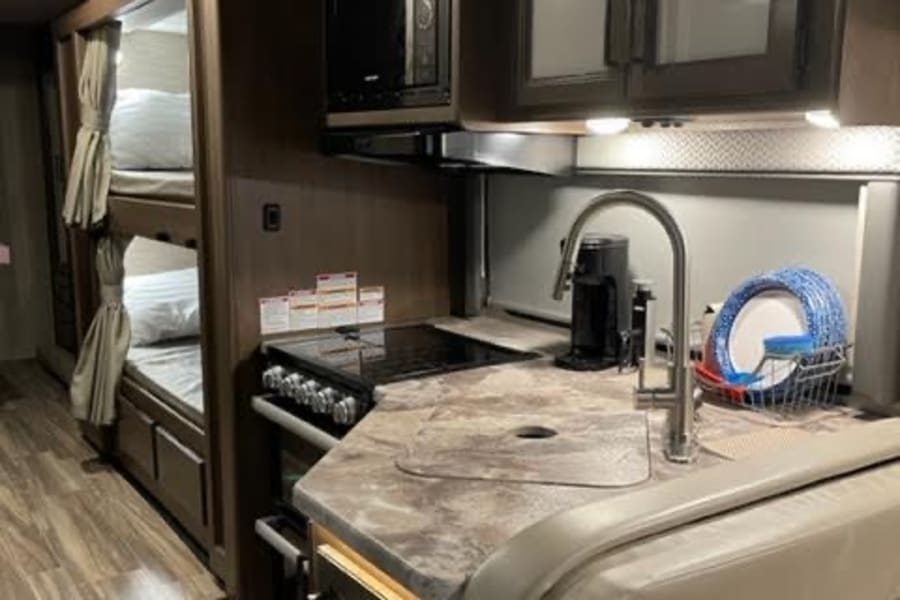 Explore an RV rental's well-equipped kitchen with microwave & sink, plus cozy bunk beds & a dinette for comfy travel.