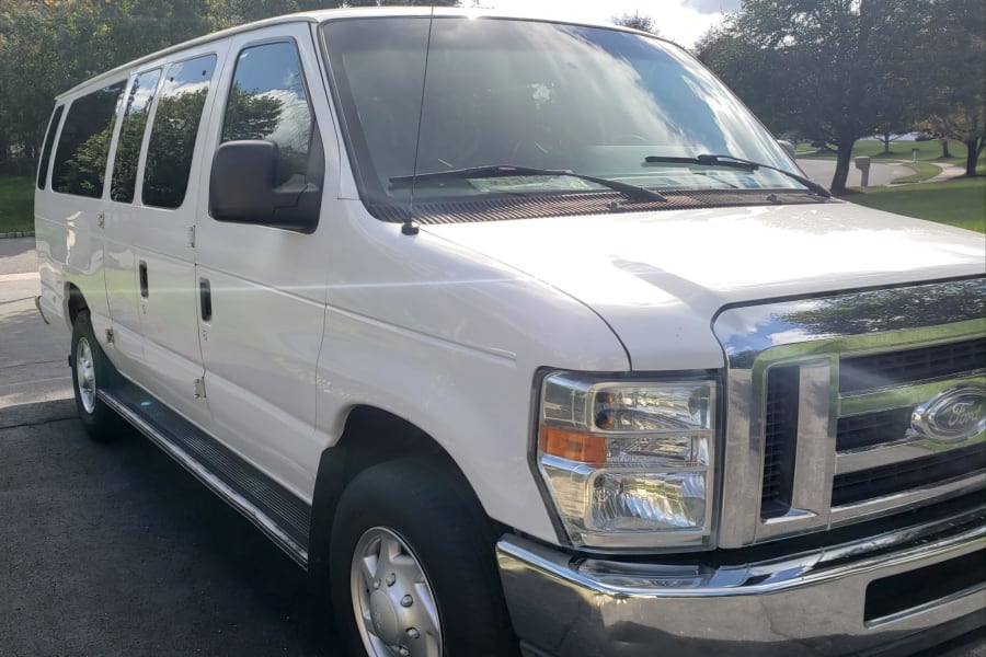 White Ford passenger van with chrome grille, great for an RV rental or a family road trip.