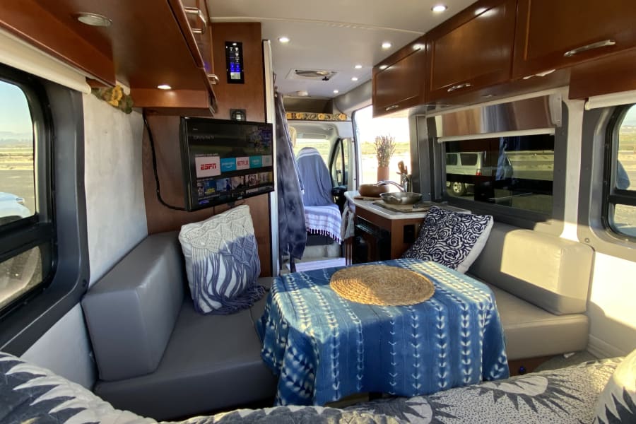 Fully equipped Lounge area with cozy seating, full memory foam couch, smart tv, dvd player & dvds in this Class B camper van