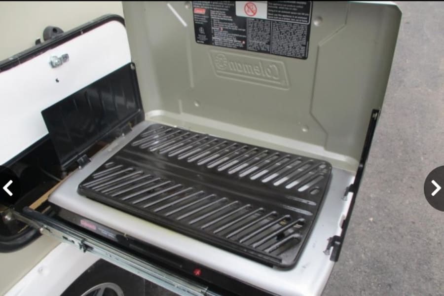 An open Coleman RoadTrip grill, part of an RV rental's outdoor kitchen setup.