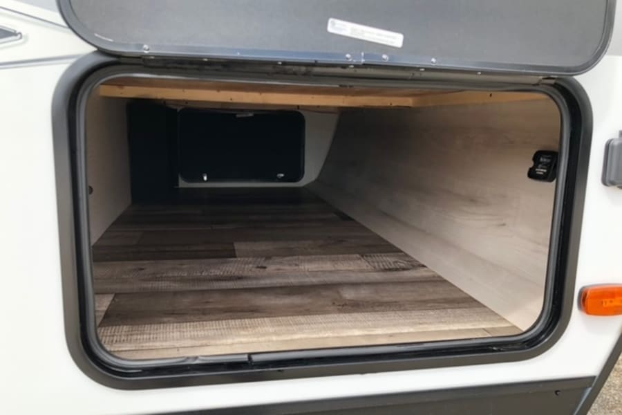 Spacious pass-through storage in this RV rental, featuring wood-look flooring and light walls. Ideal for camping gear.