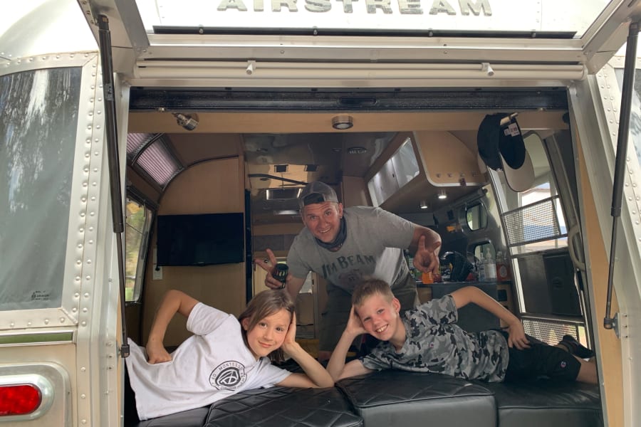 Dad and kids enjoy their Airstream rv rental. The family poses happily inside the iconic travel trailer, ready for adventure.