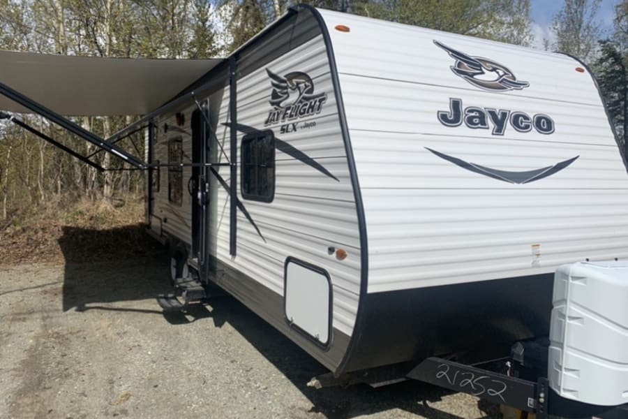 Jayco Jay Flight SLX RV rental with awning extended, parked in a scenic outdoor setting.